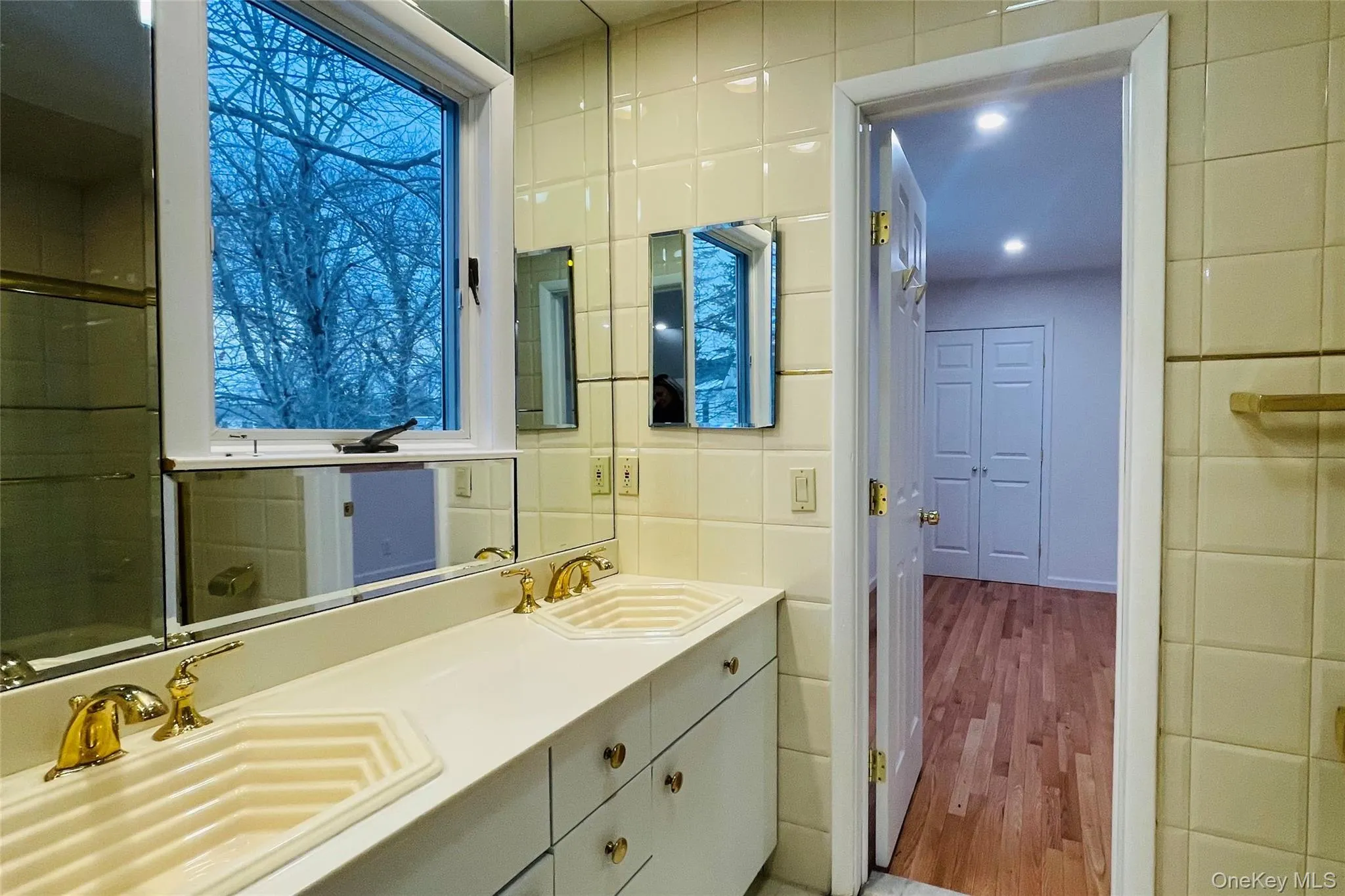 Jack-n-Jill Bathroom featuring tile walls, double vanity, an enclosed shower, and light wood-style flooring Jack-n-Jill Bathroom featuring tile walls, double vanity, an enclosed shower, and light wood-style flooring