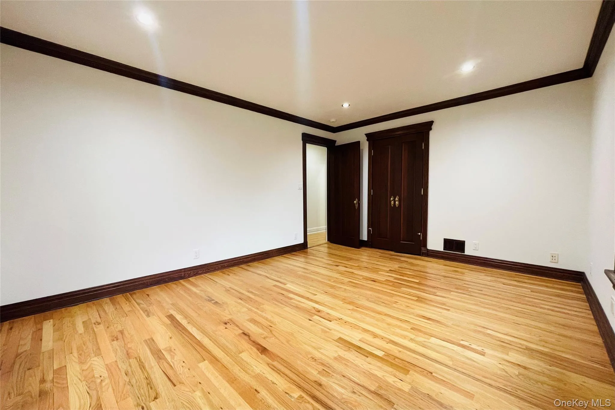Empty room with ornamental molding, light wood-style floors, and recessed lighting Empty room with ornamental molding, light wood-style floors, and recessed lighting