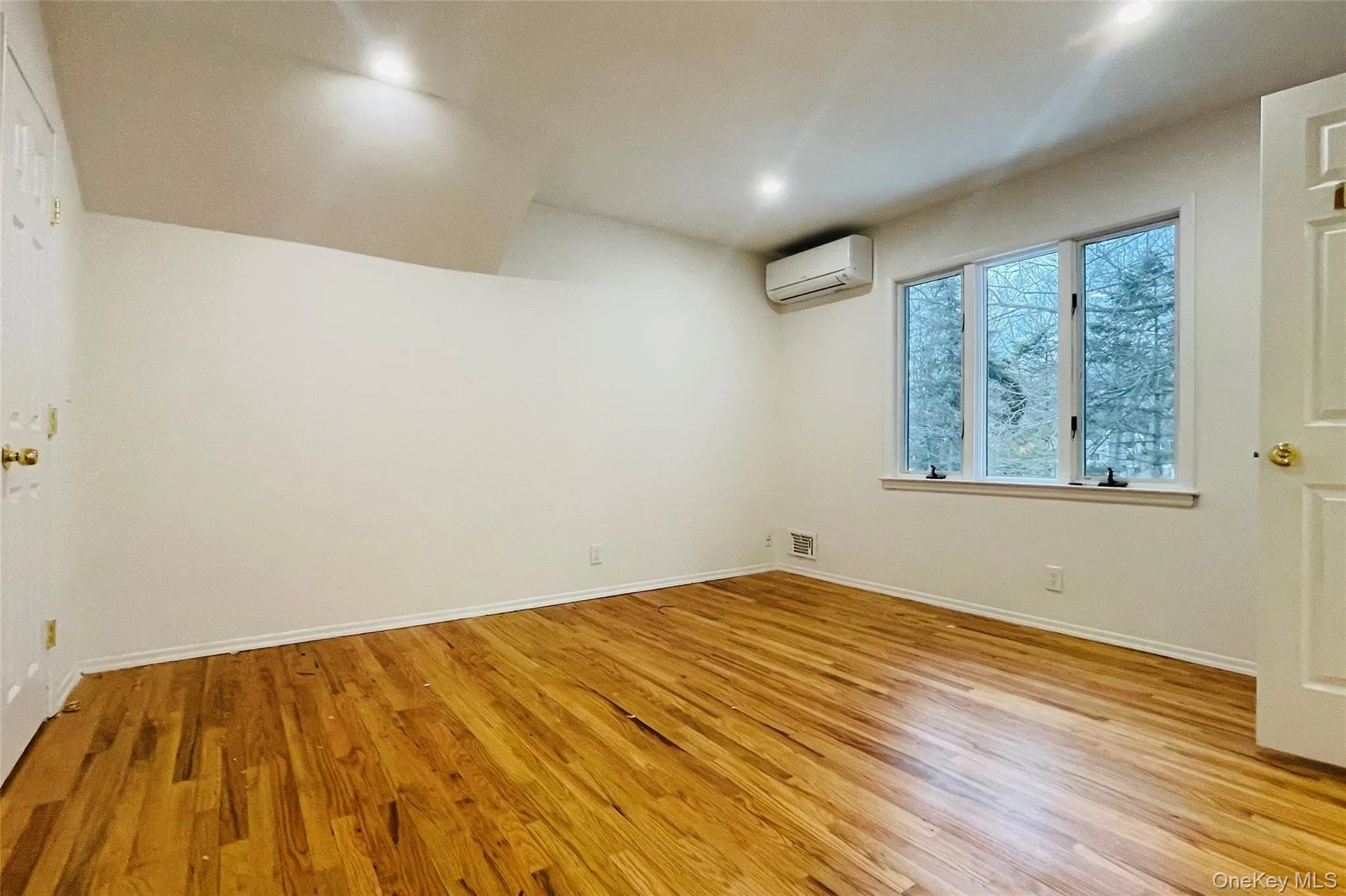 Bedroom with walk in closet featuring light wood finished floors, recessed lighting, and a wall unit AC Bedroom with walk in closet featuring light wood finished floors, recessed lighting, and a wall unit AC