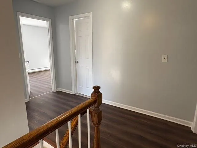 Corridor featuring an upstairs landing, dark wood-style flooring, and a baseboard radiator Corridor featuring an upstairs landing, dark wood-style flooring, and a baseboard radiator