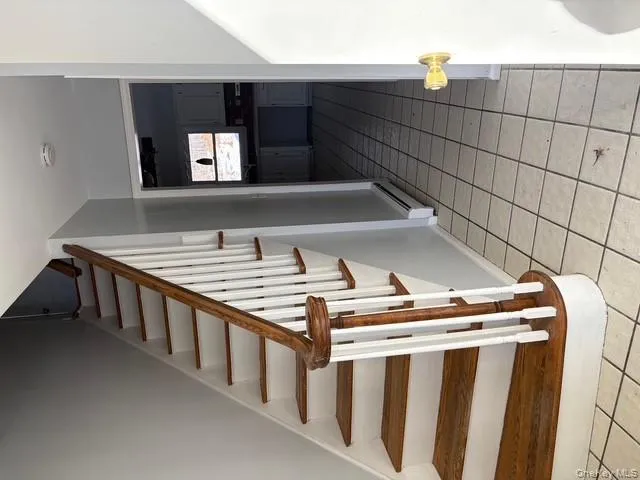 Stairs featuring tile patterned flooring and a baseboard radiator Stairs featuring tile patterned flooring and a baseboard radiator