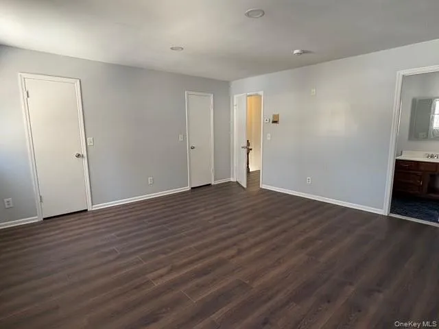 Unfurnished bedroom with connected bathroom and dark wood-type flooring Unfurnished bedroom with connected bathroom and dark wood-type flooring