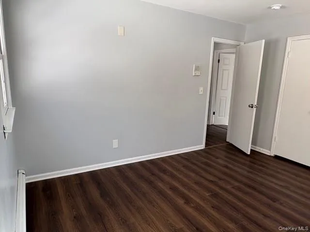Spare room featuring dark wood-style floors and baseboards Spare room featuring dark wood-style floors and baseboards