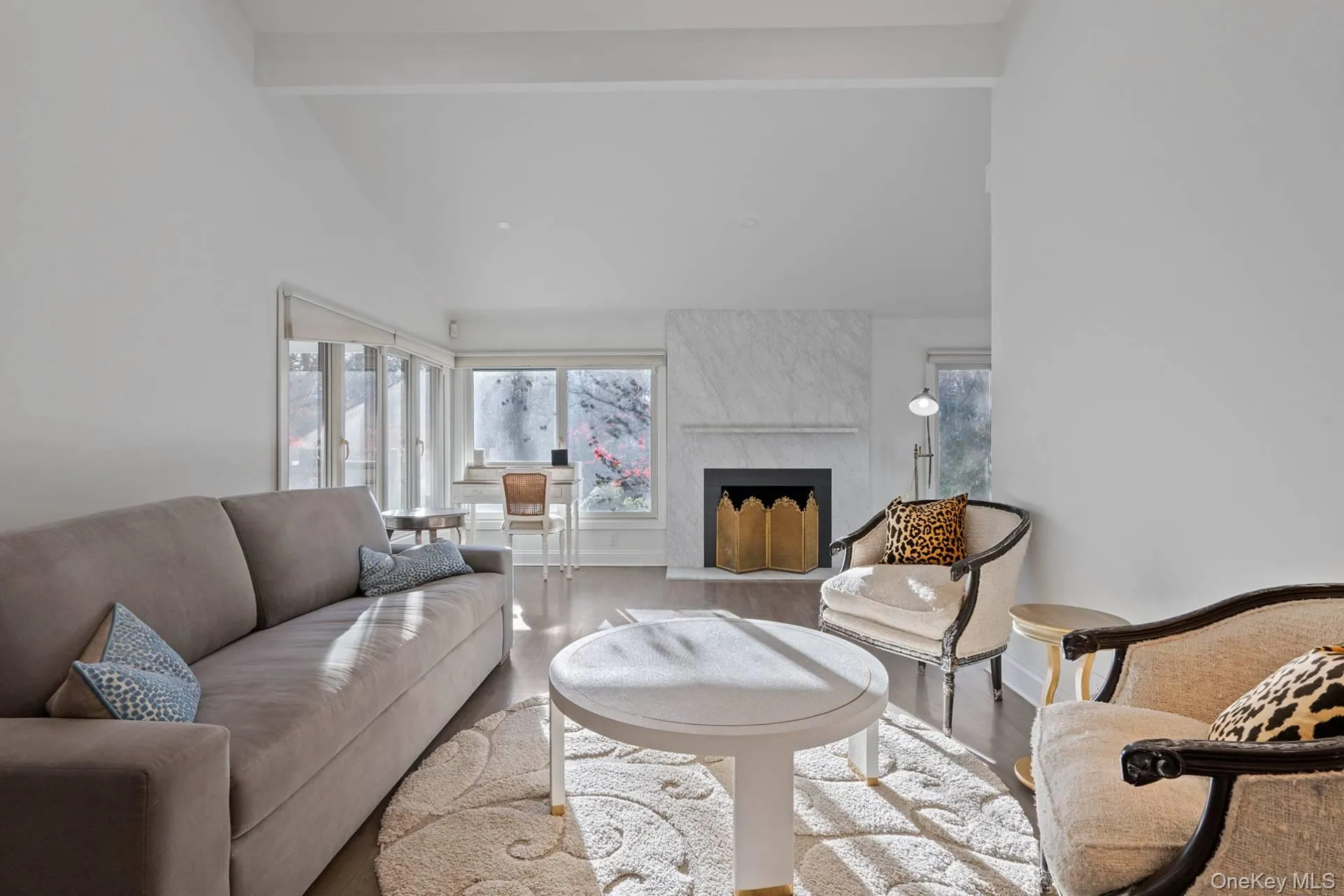 Living room featuring a high end fireplace, beam ceiling, high vaulted ceiling, and wood finished floors