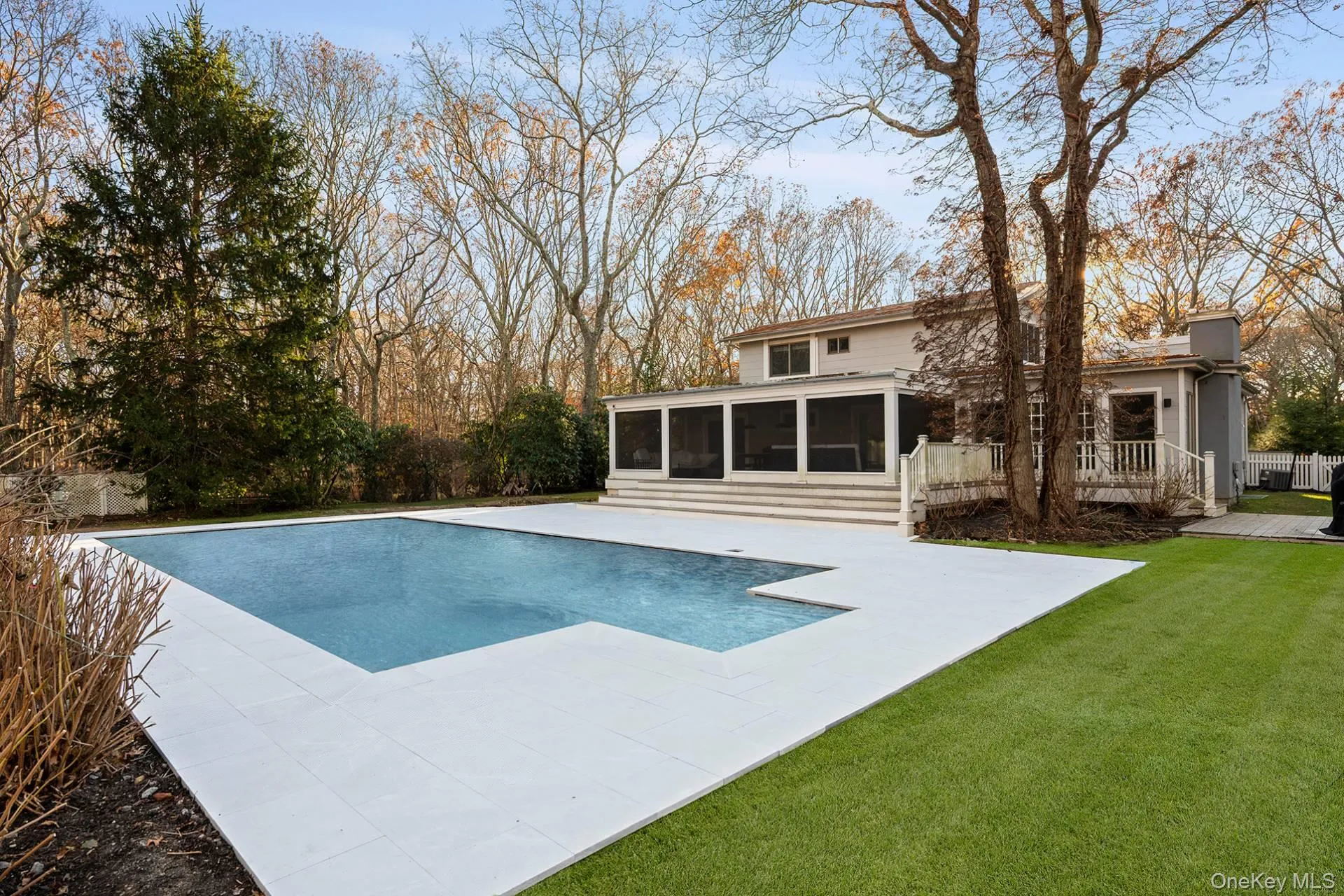 Outdoor pool with a sunroom, a patio area, and a lawn