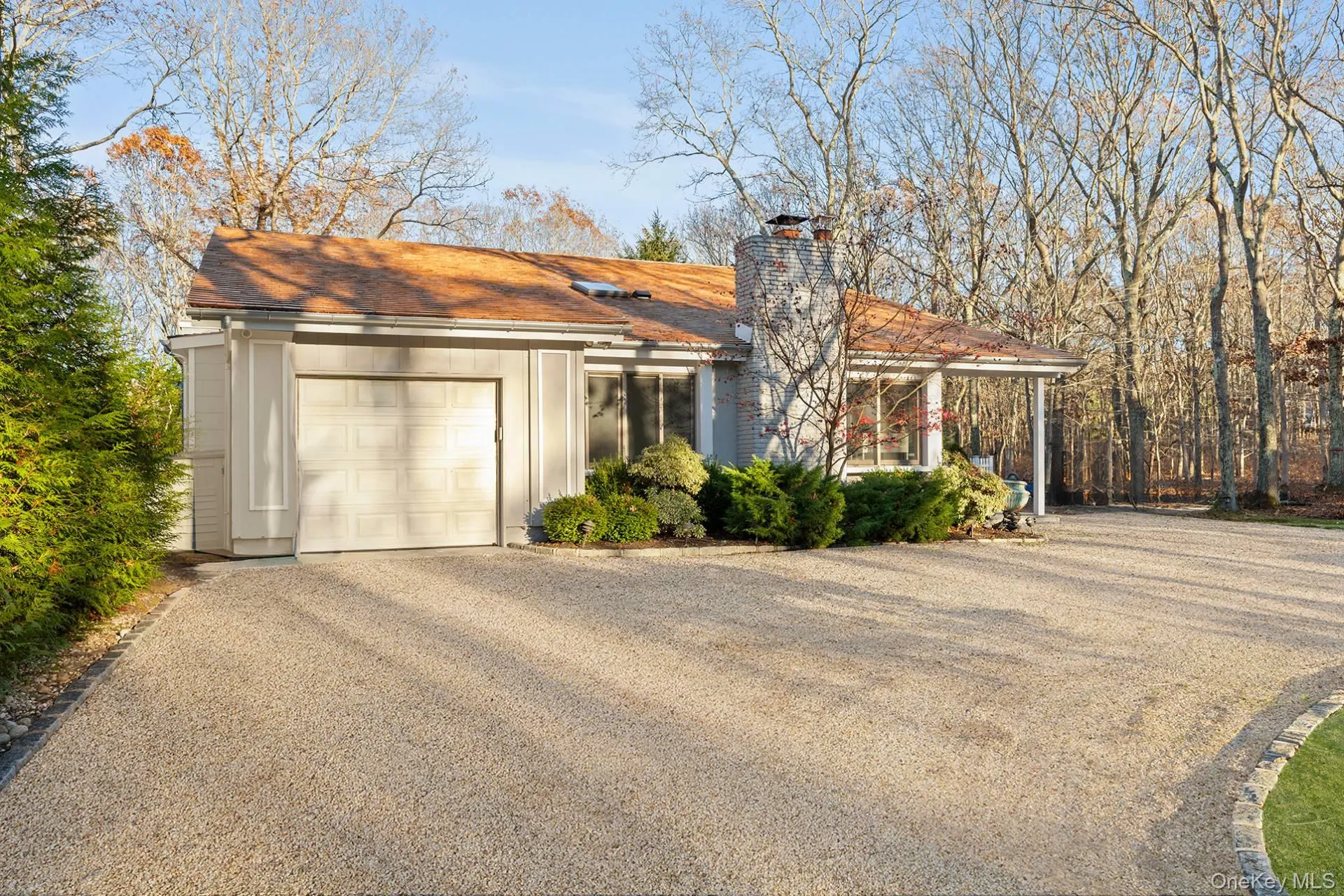 View of front of house with driveway, a chimney, and a garage