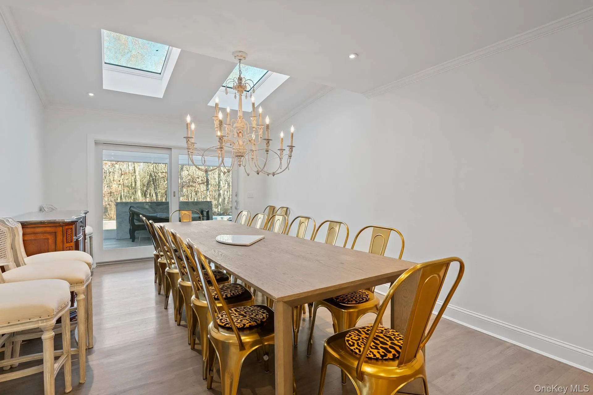 Dining room featuring a skylight, a chandelier, crown molding, and wood finished floors