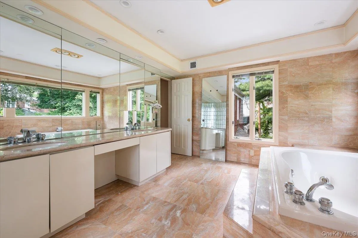 Bathroom featuring a whirlpool tub, tile walls, and double vanity Bathroom featuring a whirlpool tub, tile walls, and double vanity