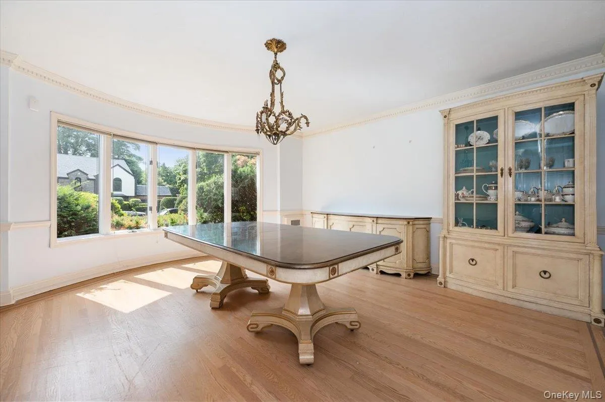 Dining space featuring light wood finished floors, a chandelier, ornamental molding, and a wainscoted wall Dining space featuring light wood finished floors, a chandelier, ornamental molding, and a wainscoted wall
