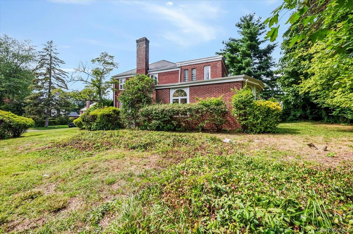 View of property exterior featuring brick siding, a chimney, and a yard View of property exterior featuring brick siding, a chimney, and a yard