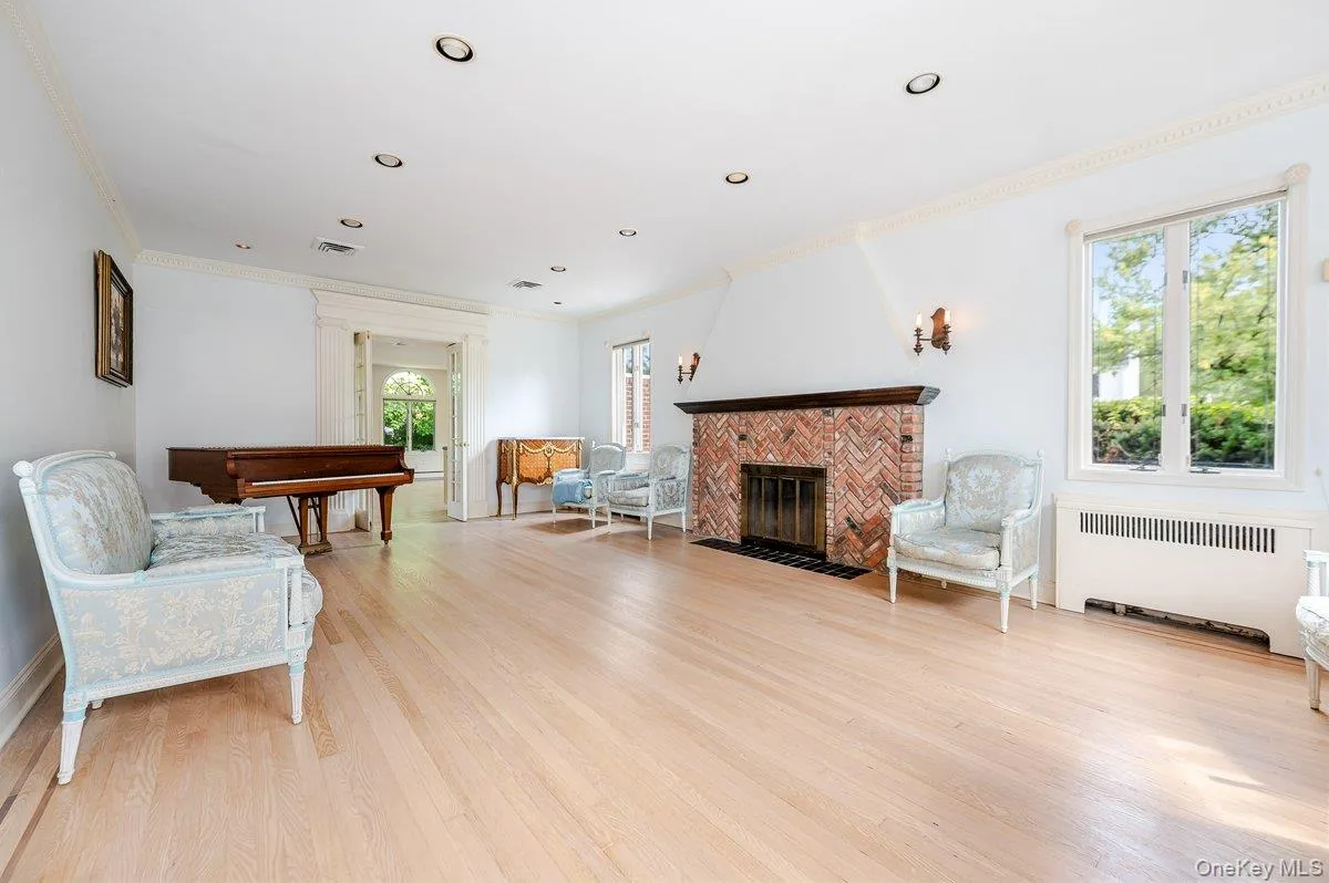 Living room featuring a brick fireplace, radiator, light wood-style floors, crown molding, and recessed lighting Living room featuring a brick fireplace, radiator, light wood-style floors, crown molding, and recessed lighting