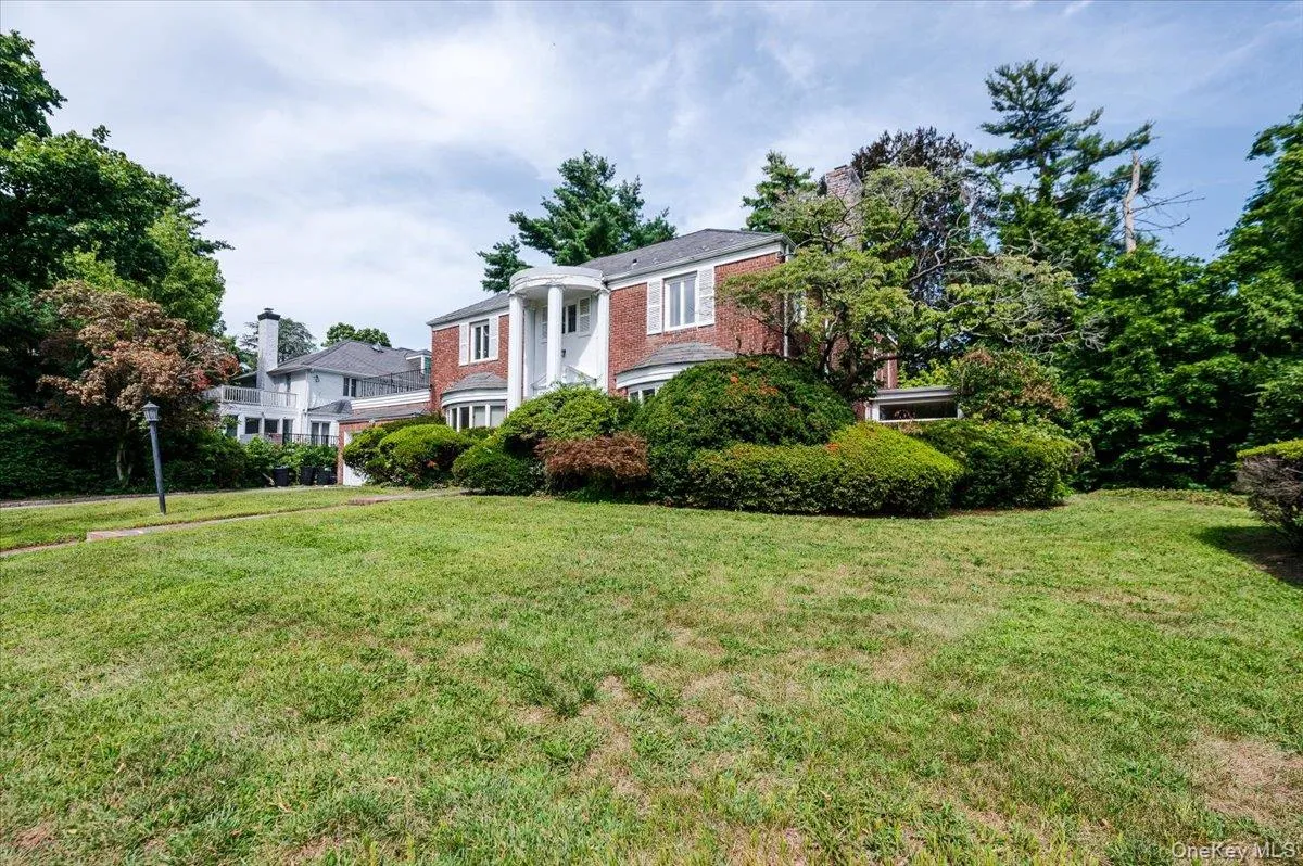 Greek revival house featuring a front yard, brick siding, and a chimney Greek revival house featuring a front yard, brick siding, and a chimney