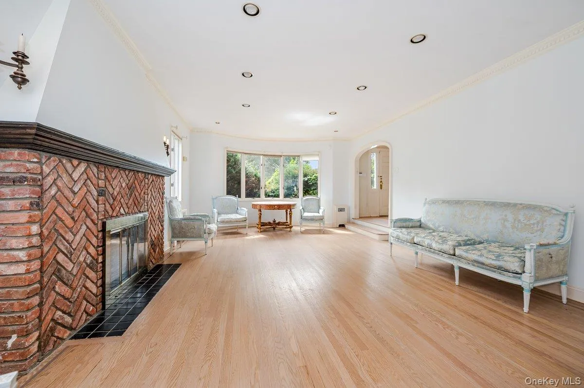 Living area with crown molding, arched walkways, light wood-style floors, and a fireplace with flush hearth Living area with crown molding, arched walkways, light wood-style floors, and a fireplace with flush hearth