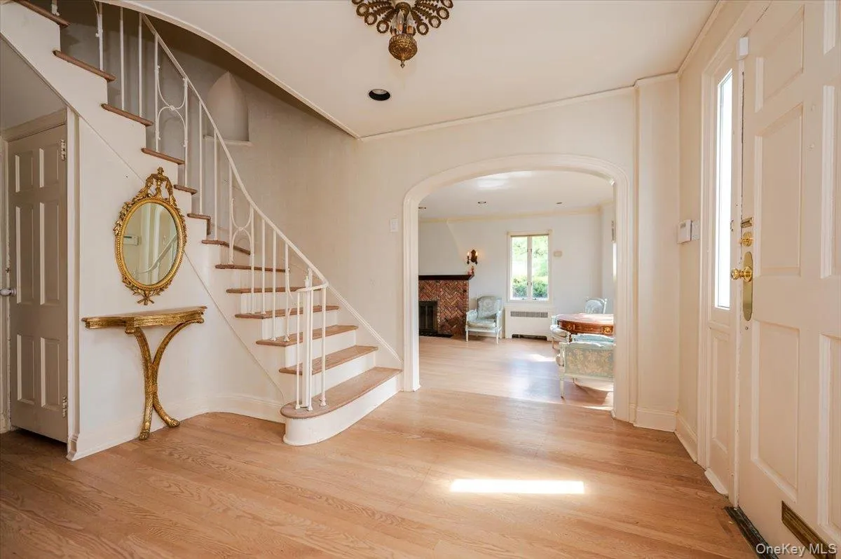 Foyer with light wood-style floors, a tiled fireplace, radiator heating unit, and stairs Foyer with light wood-style floors, a tiled fireplace, radiator heating unit, and stairs