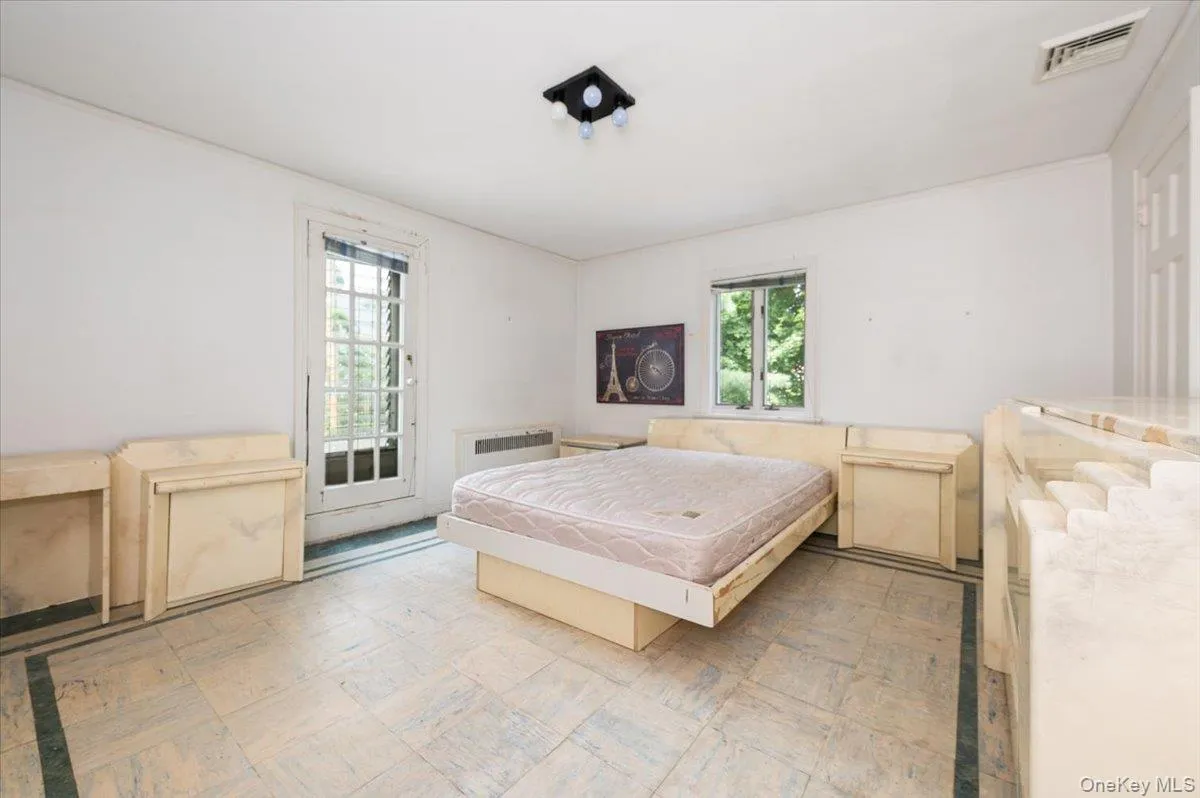 Bedroom with access to exterior, light floors, and radiator Bedroom with access to exterior, light floors, and radiator