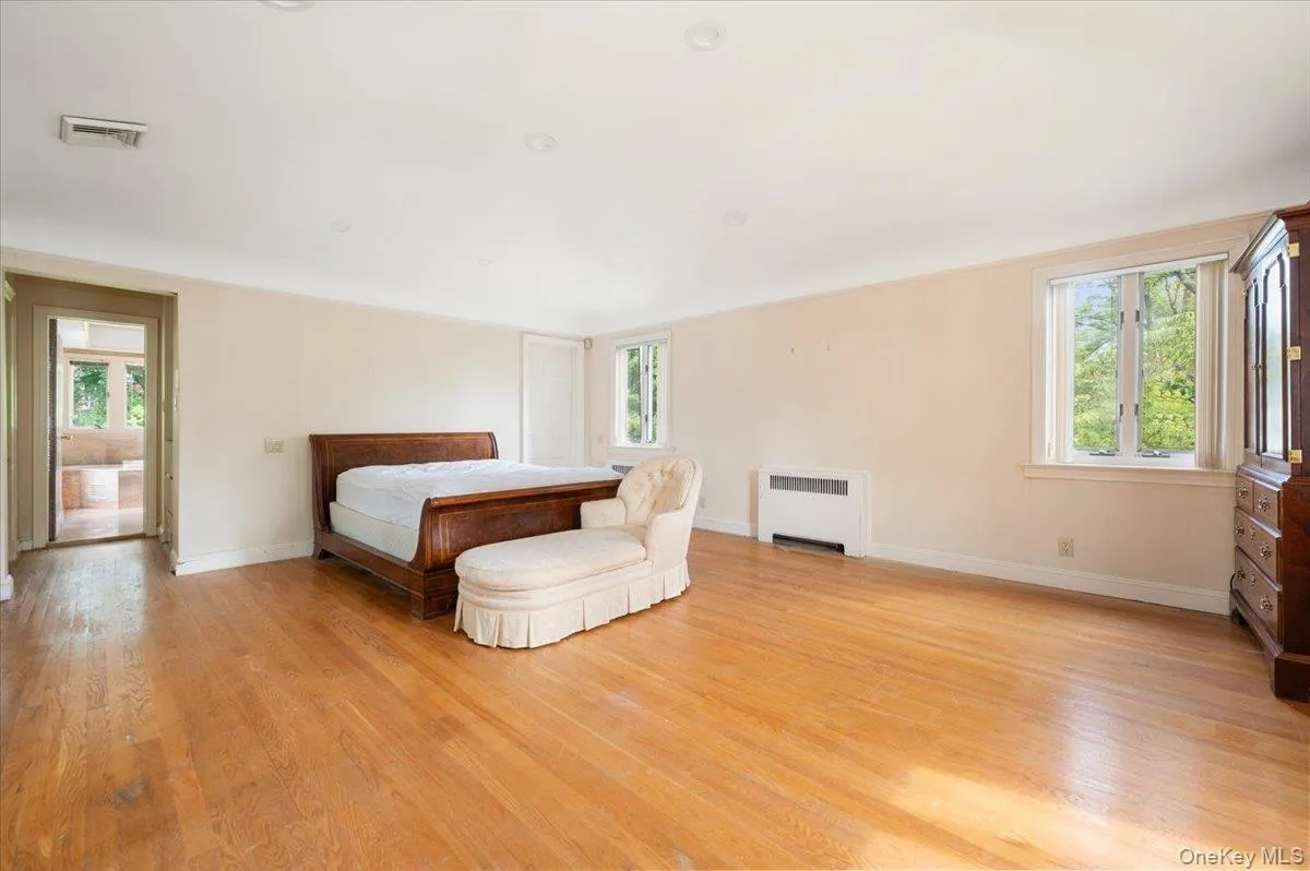 Bedroom with radiator heating unit and light wood-style flooring Bedroom with radiator heating unit and light wood-style flooring