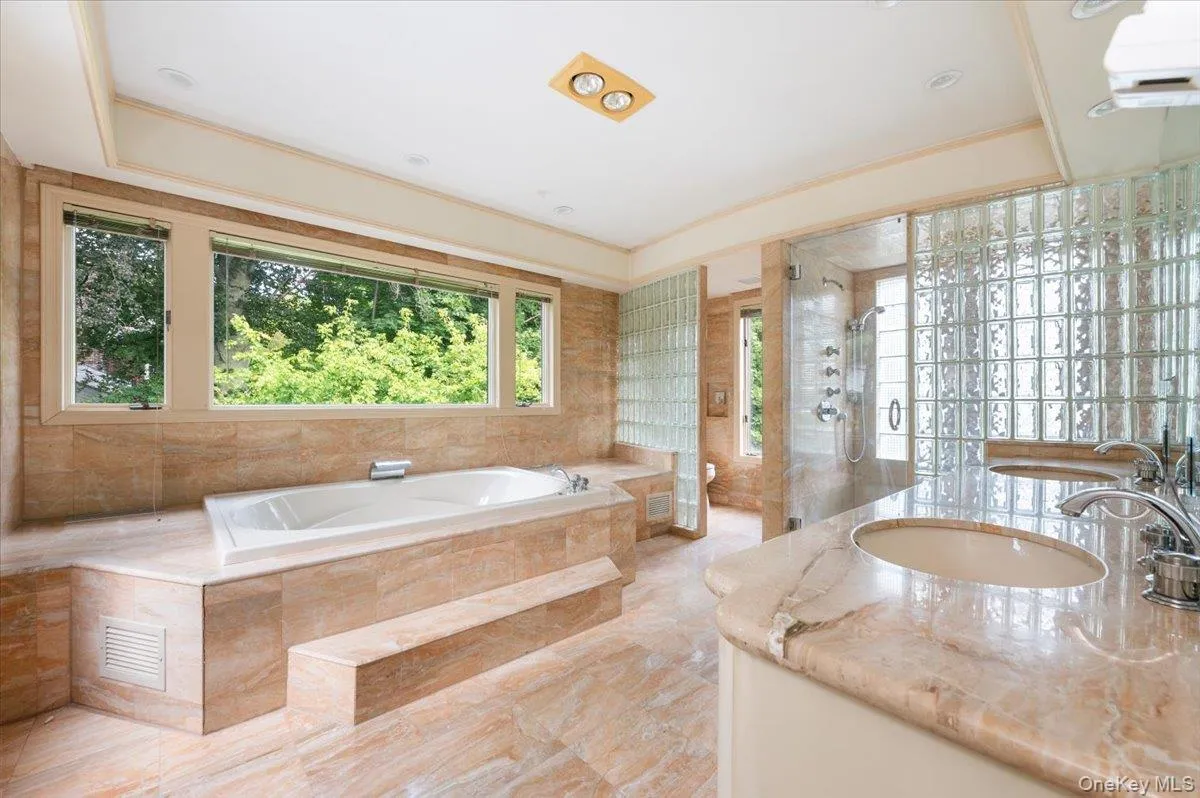 Bathroom featuring a shower stall, vanity, a bath, a wall unit AC, and tile walls Bathroom featuring a shower stall, vanity, a bath, a wall unit AC, and tile walls