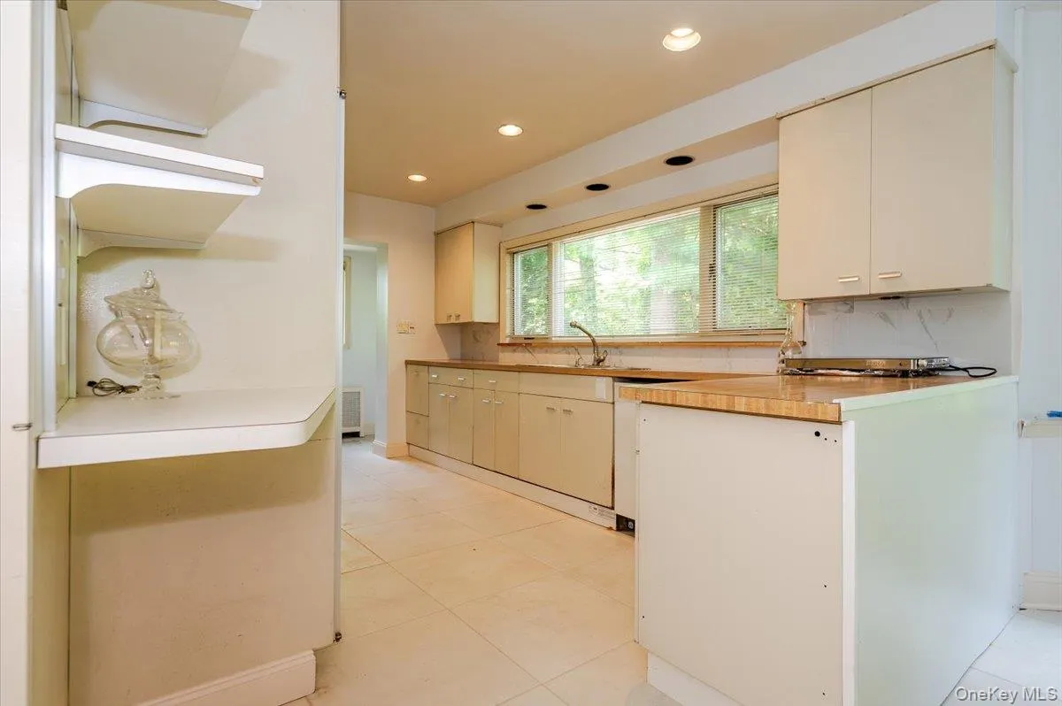 Kitchen featuring recessed lighting, light countertops, decorative backsplash, white dishwasher, and light tile patterned floors Kitchen featuring recessed lighting, light countertops, decorative backsplash, white dishwasher, and light tile patterned floors