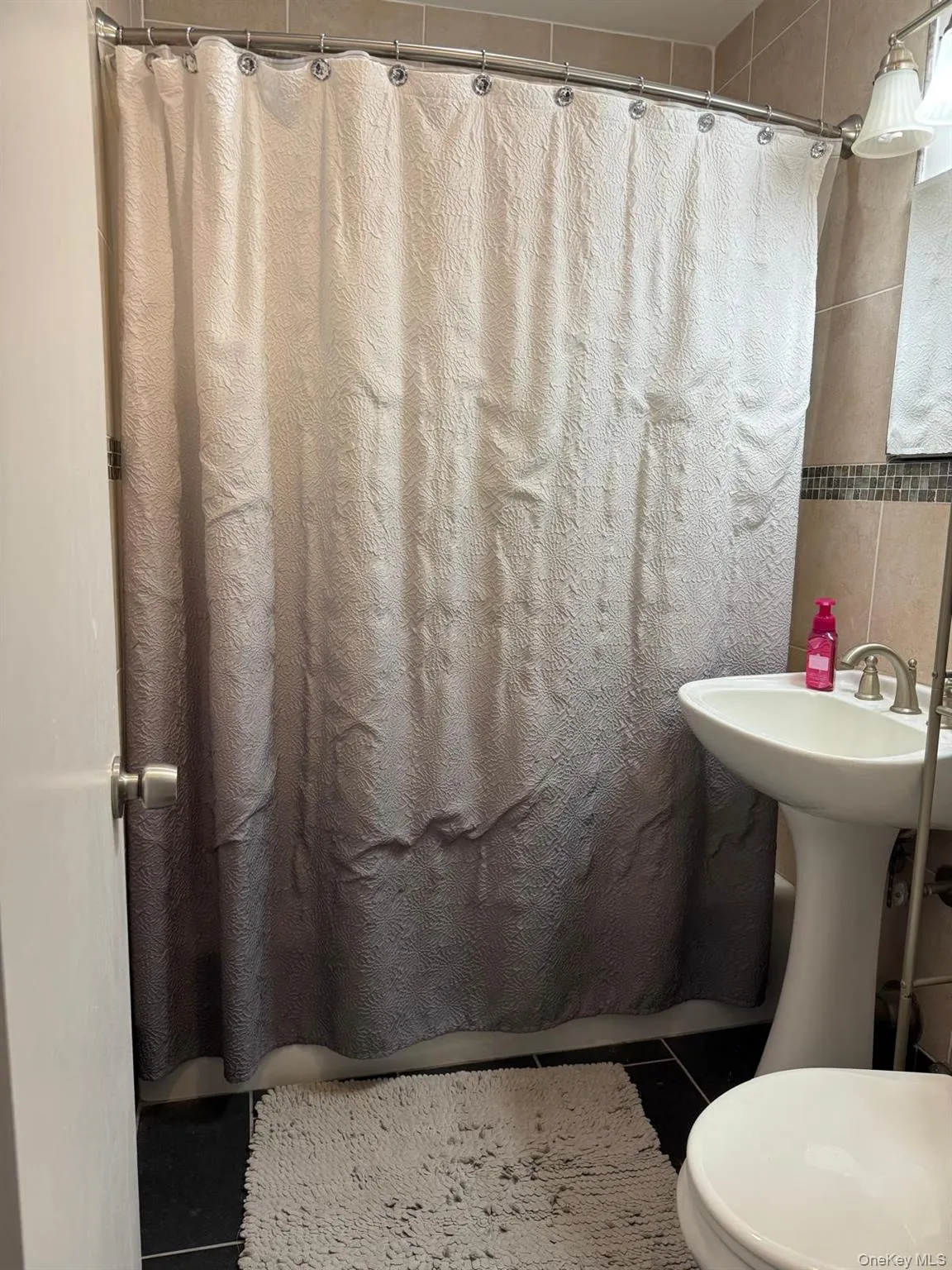 Full bath featuring tile patterned flooring and tile walls Full bath featuring tile patterned flooring and tile walls