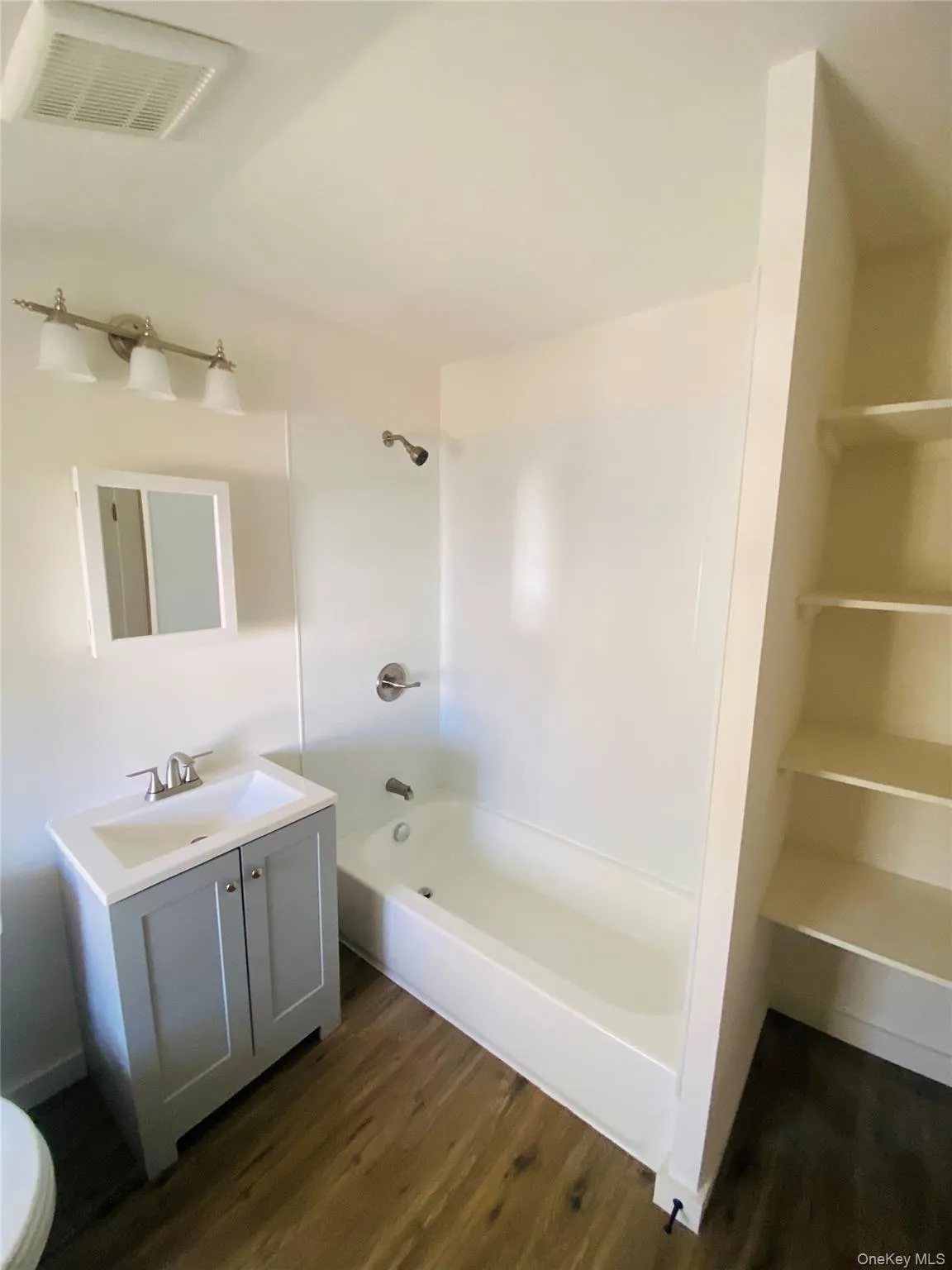 Bathroom with vanity, dark wood-style floors, and shower / washtub combination Bathroom with vanity, dark wood-style floors, and shower / washtub combination