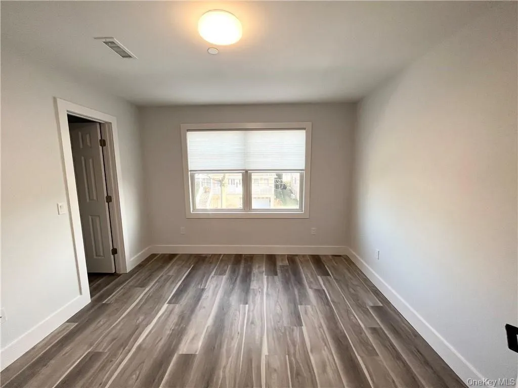 Unfurnished room with dark wood-style flooring and baseboards Unfurnished room with dark wood-style flooring and baseboards