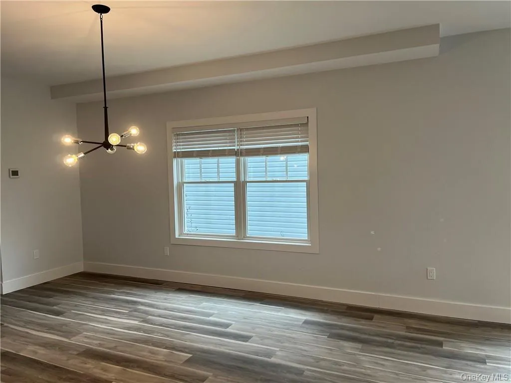 Empty room featuring a chandelier and dark wood-type flooring Empty room featuring a chandelier and dark wood-type flooring