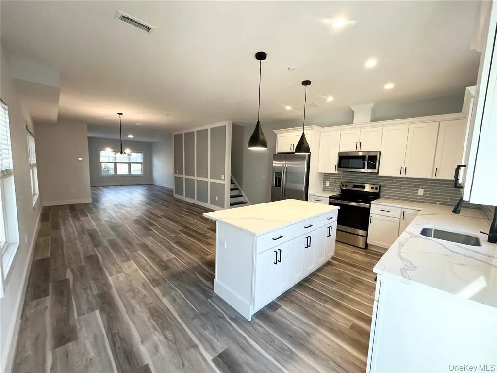 Kitchen with stainless steel appliances, pendant lighting, a center island, backsplash, and open floor plan Kitchen with stainless steel appliances, pendant lighting, a center island, backsplash, and open floor plan