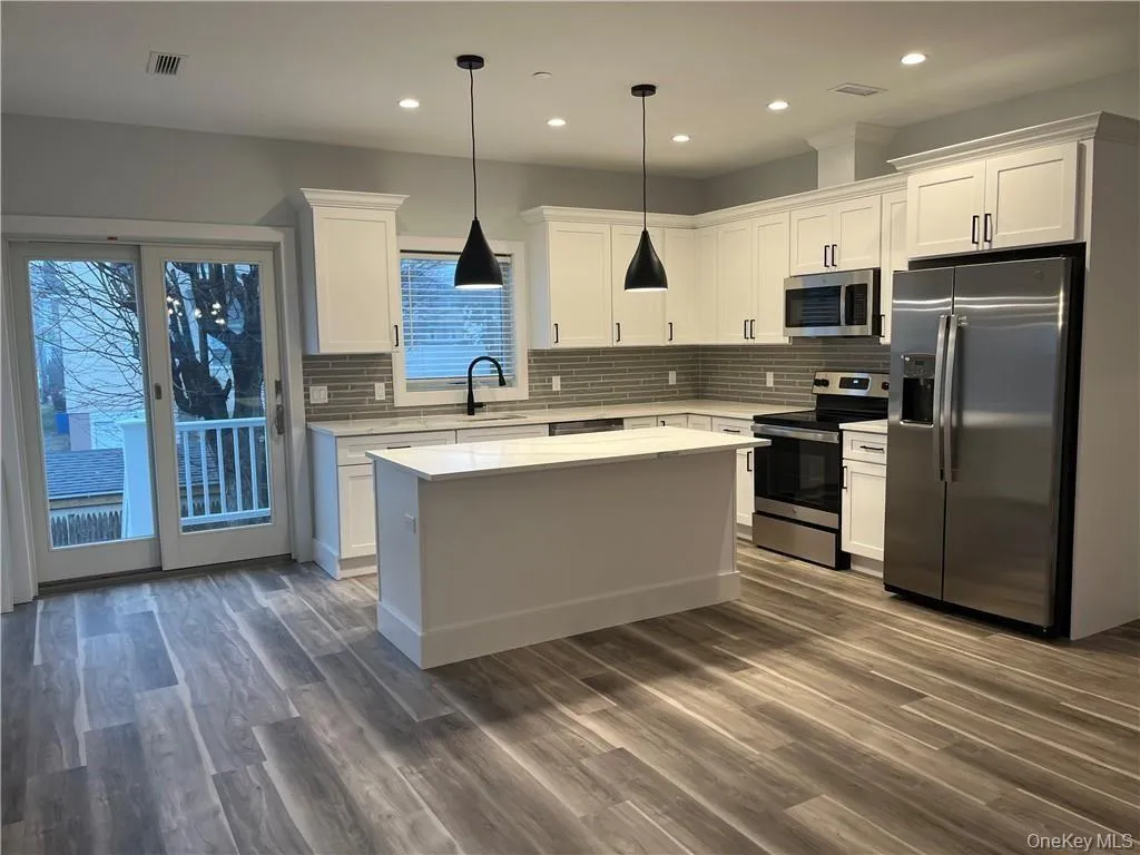 Kitchen featuring stainless steel appliances, white cabinets, a center island, decorative backsplash, and recessed lighting Kitchen featuring stainless steel appliances, white cabinets, a center island, decorative backsplash, and recessed lighting