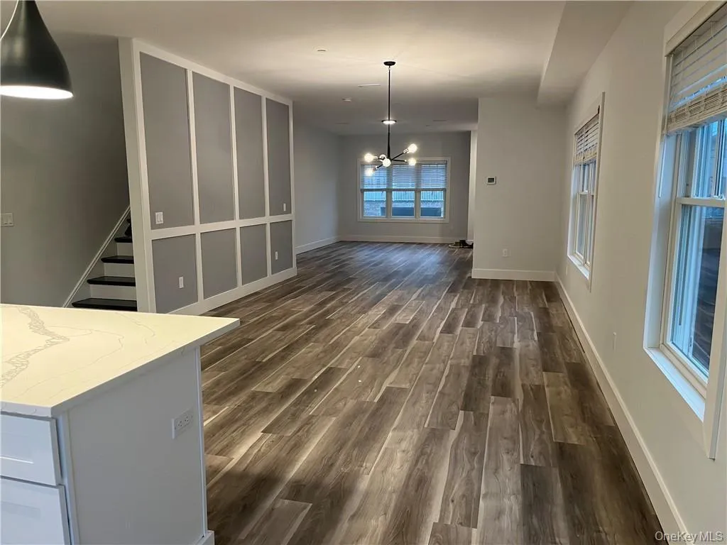 Unfurnished dining area with a chandelier, dark wood-type flooring, and stairs Unfurnished dining area with a chandelier, dark wood-type flooring, and stairs