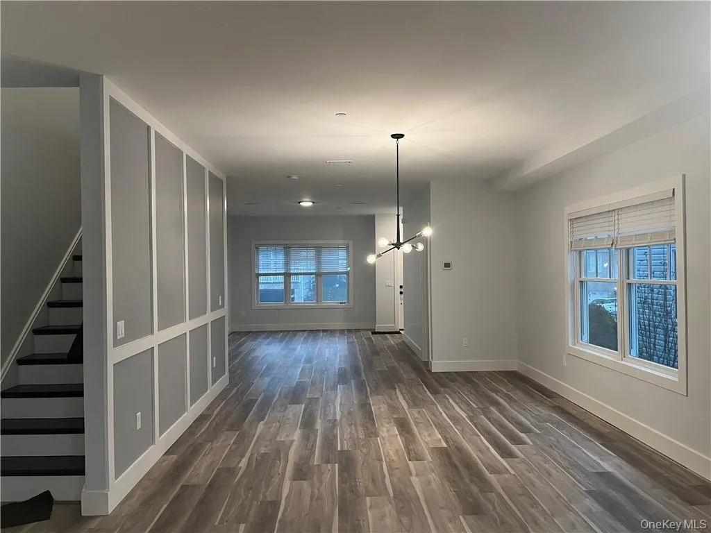Unfurnished dining area with dark wood-type flooring, stairway, and a chandelier Unfurnished dining area with dark wood-type flooring, stairway, and a chandelier