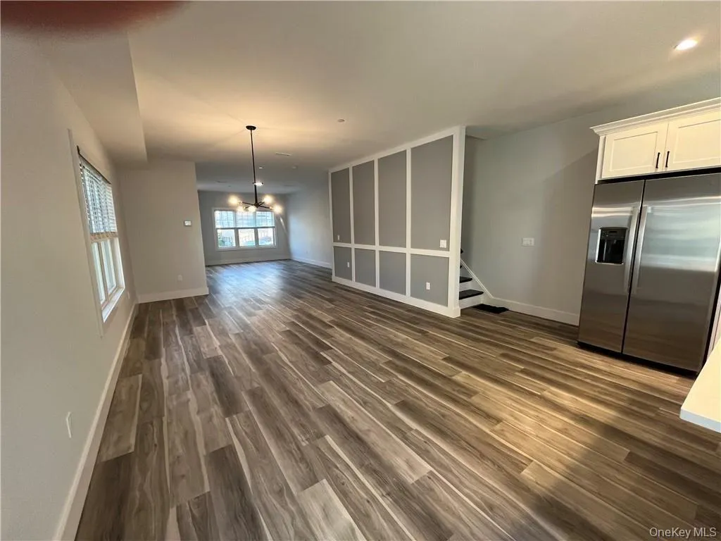 Unfurnished living room with dark wood finished floors, a chandelier, and stairs Unfurnished living room with dark wood finished floors, a chandelier, and stairs