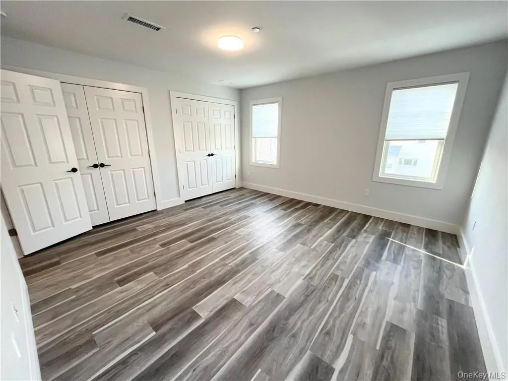 Unfurnished bedroom featuring two closets and dark wood finished floors Unfurnished bedroom featuring two closets and dark wood finished floors