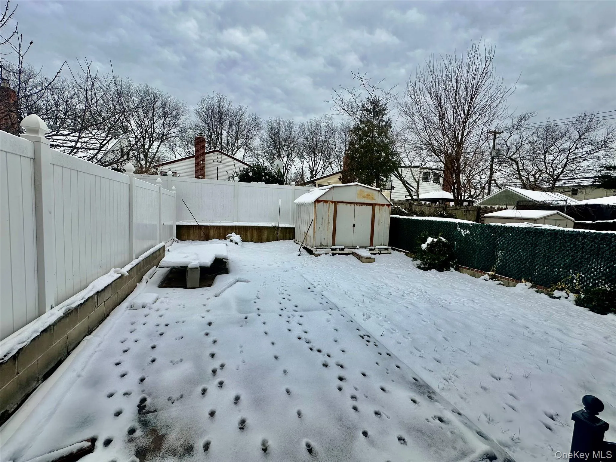 Yard layered in snow featuring a fenced backyard and a storage shed Yard layered in snow featuring a fenced backyard and a storage shed