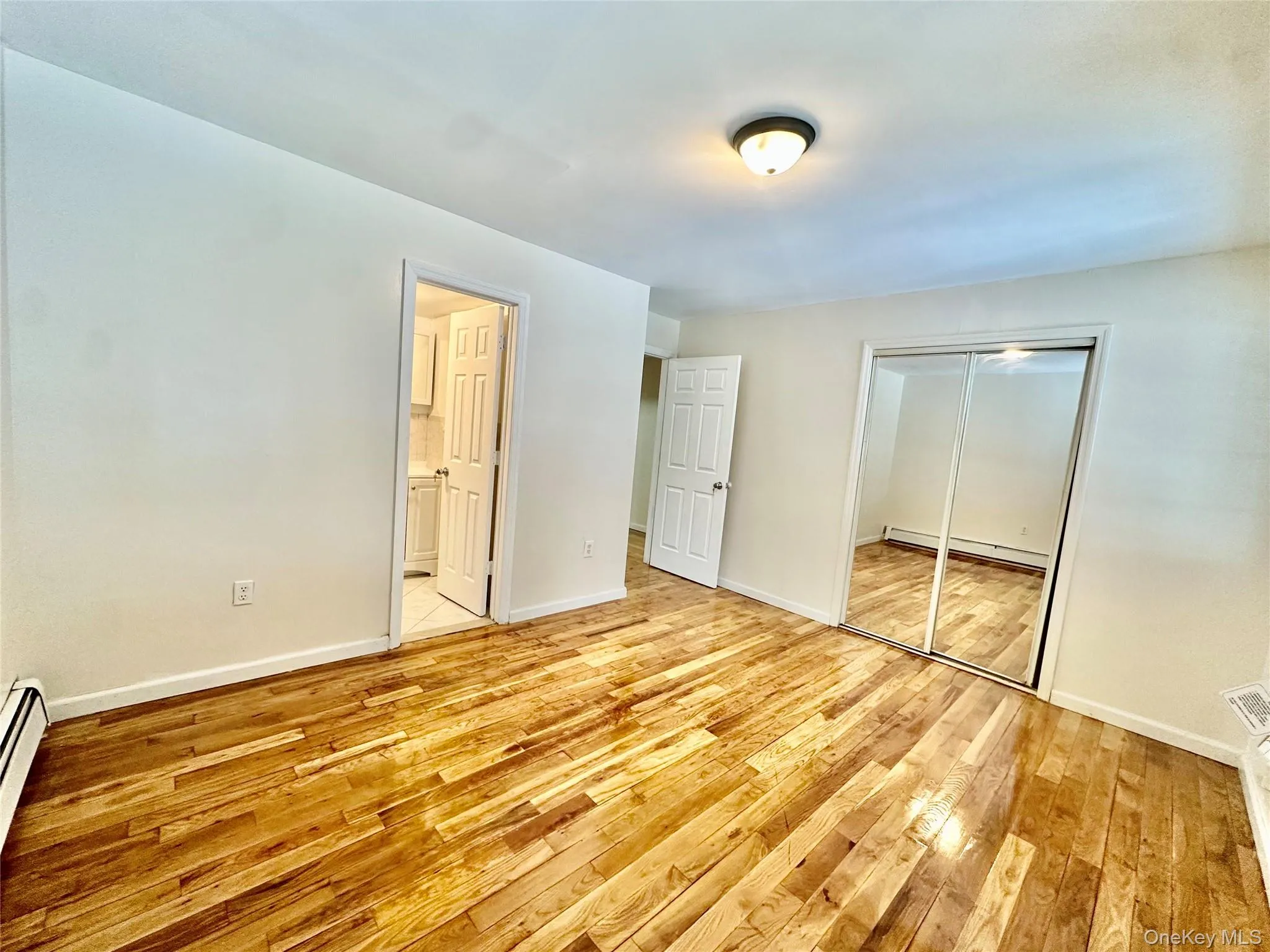 Unfurnished bedroom featuring light wood-style flooring, a closet, and a baseboard radiator Unfurnished bedroom featuring light wood-style flooring, a closet, and a baseboard radiator