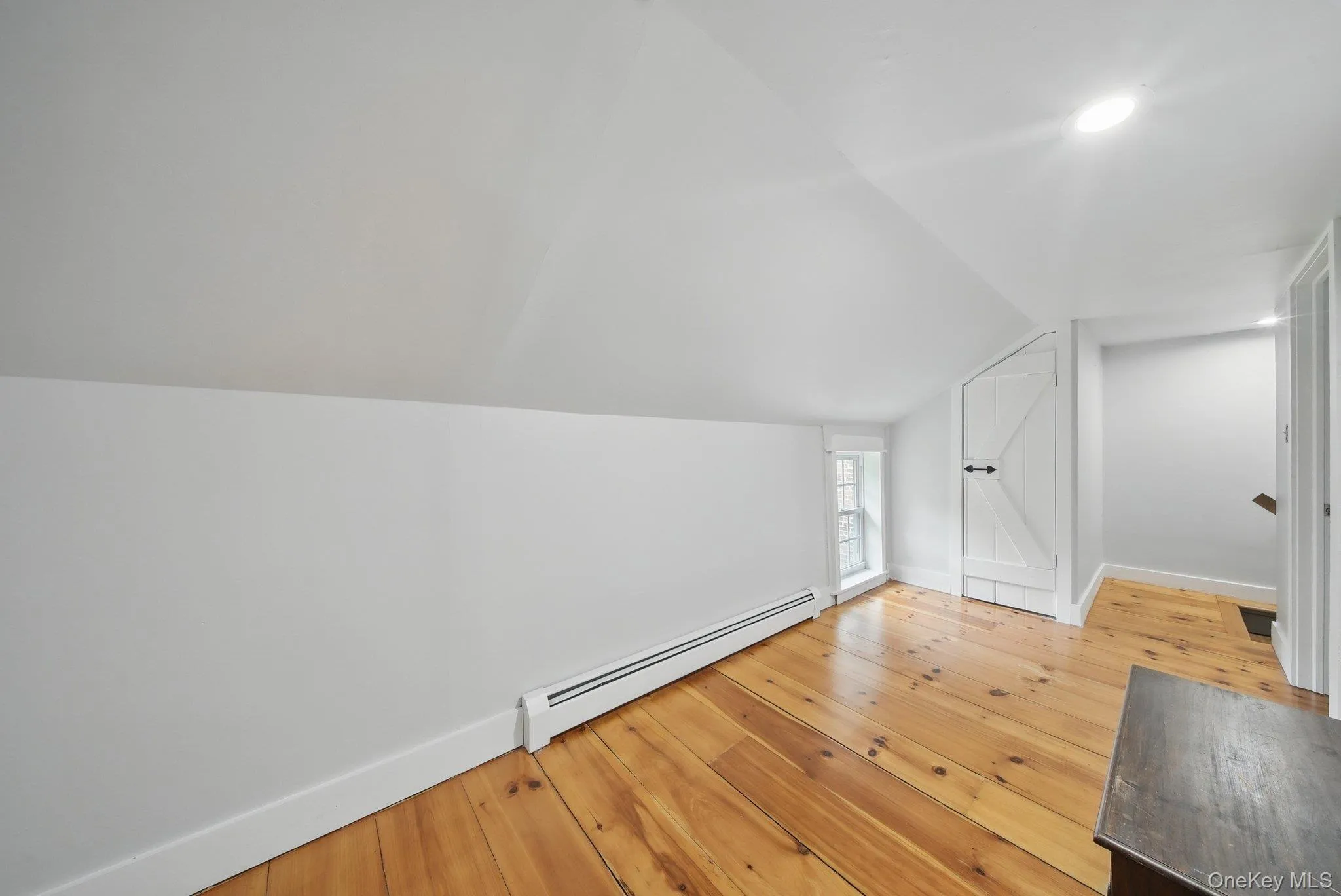 Additional living space with a baseboard radiator, light wood-style floors, and lofted ceiling Additional living space with a baseboard radiator, light wood-style floors, and lofted ceiling