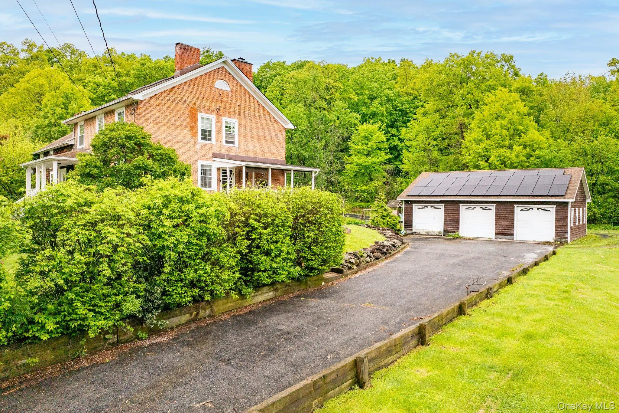 View of side of property featuring an outdoor structure, a lawn, a detached garage, a chimney, and brick siding View of side of property featuring an outdoor structure, a lawn, a detached garage, a chimney, and brick siding