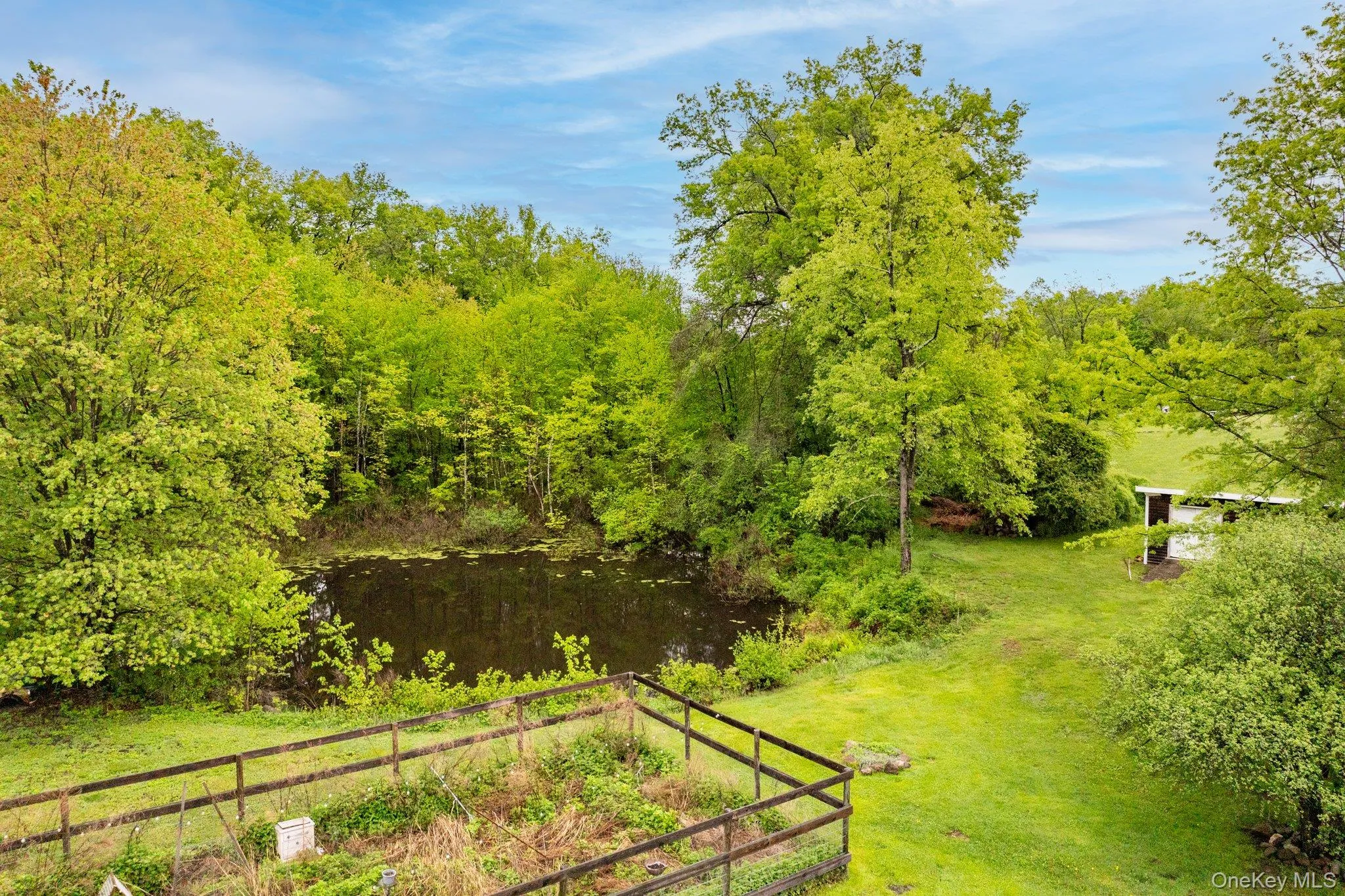 View of grassy yard featuring a water view, a garden, and a wooded view View of grassy yard featuring a water view, a garden, and a wooded view