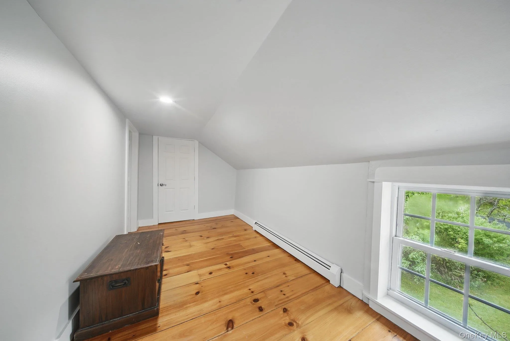Additional living space with a baseboard heating unit, lofted ceiling, and light wood-type flooring Additional living space with a baseboard heating unit, lofted ceiling, and light wood-type flooring