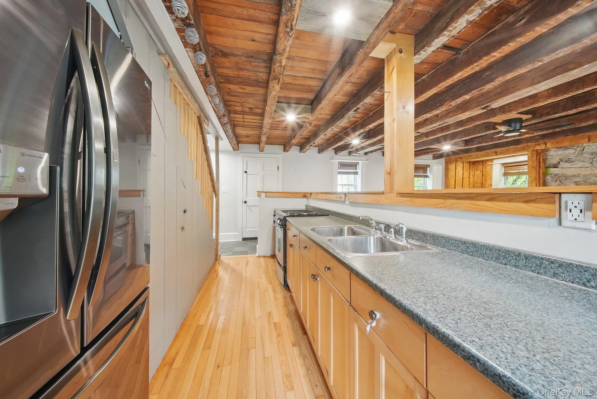 Kitchen with stainless steel appliances, a wooden ceiling with exposed beams, and light wood-style flooring Kitchen with stainless steel appliances, a wooden ceiling with exposed beams, and light wood-style flooring