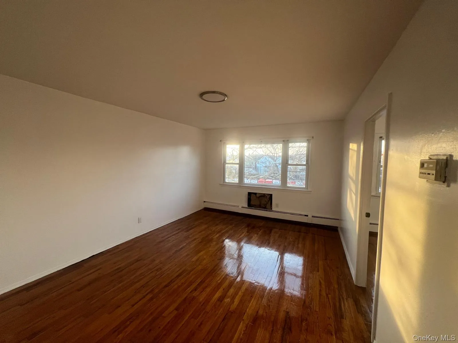 Unfurnished room featuring dark wood-type flooring and a baseboard radiator Unfurnished room featuring dark wood-type flooring and a baseboard radiator