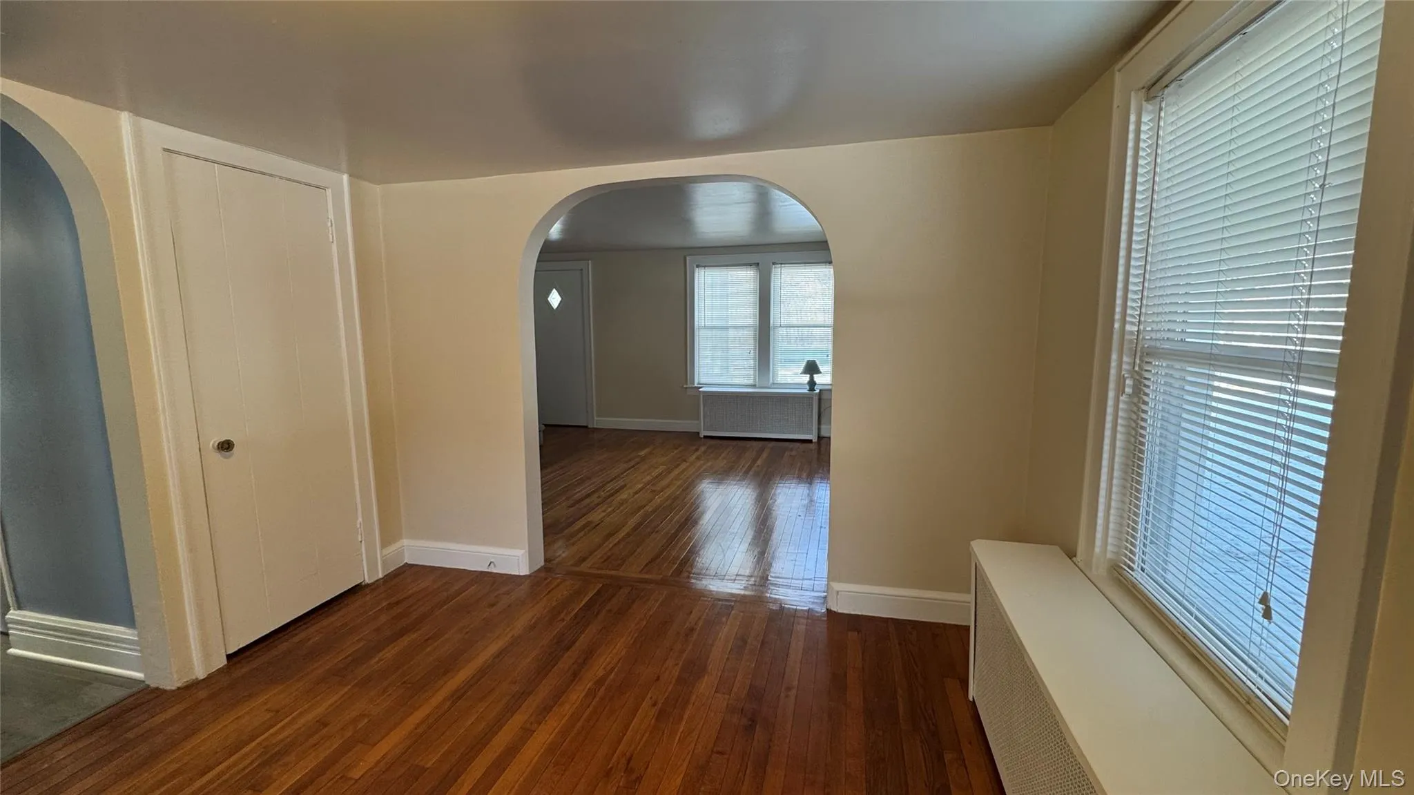 Corridor featuring dark wood-type flooring, radiator heating unit, and arched walkways Corridor featuring dark wood-type flooring, radiator heating unit, and arched walkways