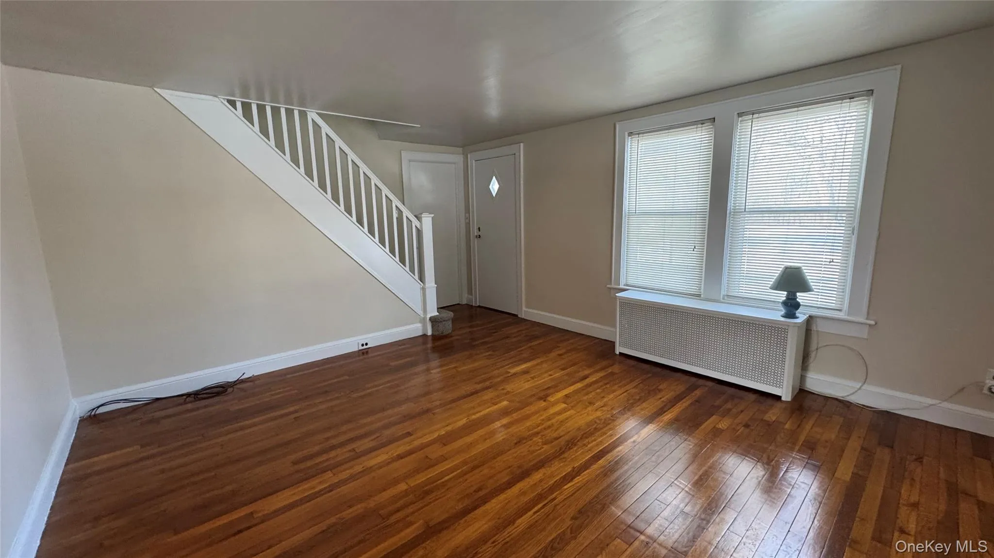 Entrance foyer featuring stairway, radiator heating unit, and dark wood-type flooring Entrance foyer featuring stairway, radiator heating unit, and dark wood-type flooring