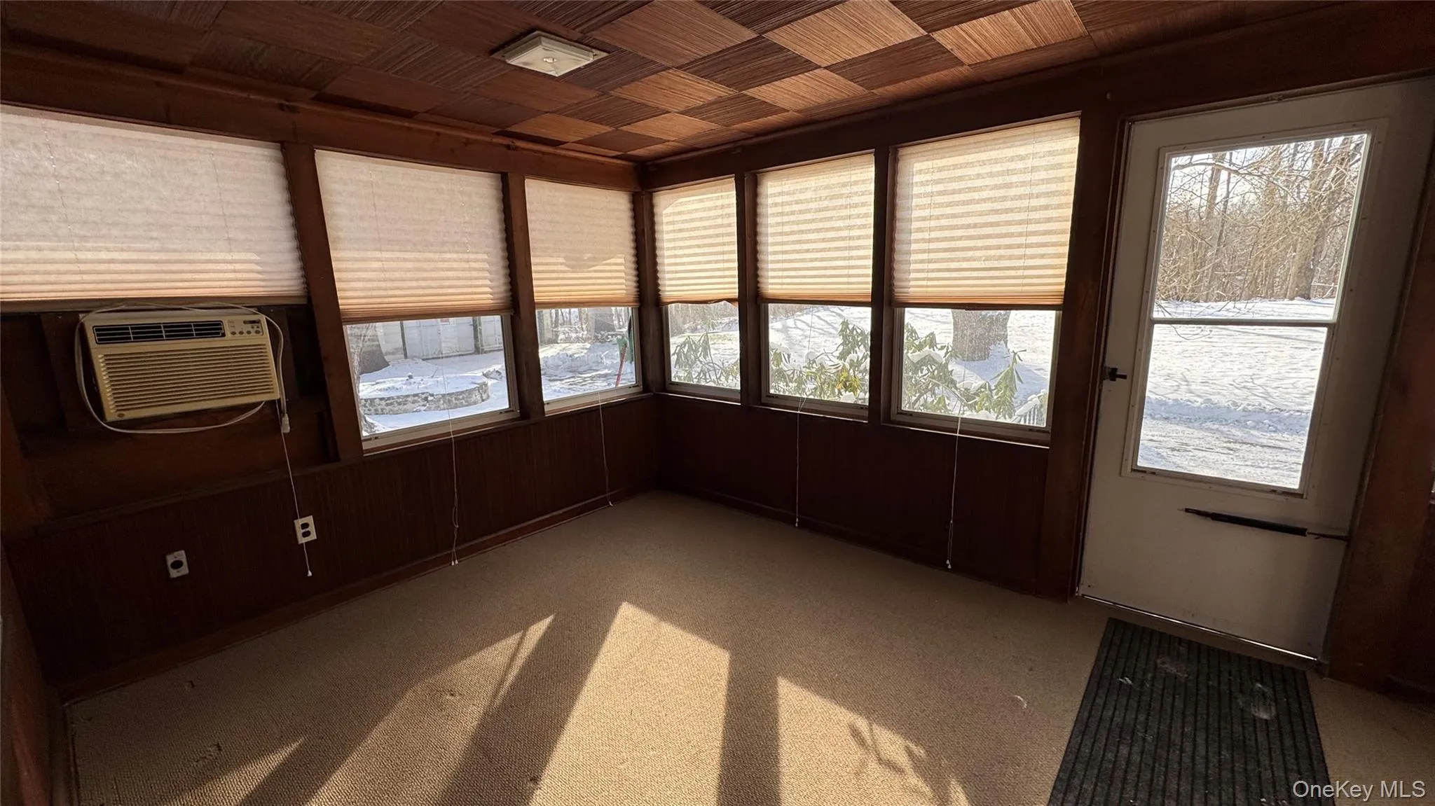 Unfurnished sunroom featuring healthy amount of natural light, carpet floors, wood walls, and wooden ceiling Unfurnished sunroom featuring healthy amount of natural light, carpet floors, wood walls, and wooden ceiling