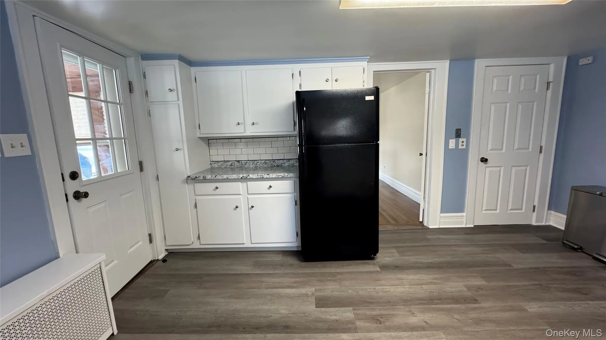 Kitchen with freestanding refrigerator, white cabinets, light countertops, and tasteful backsplash Kitchen with freestanding refrigerator, white cabinets, light countertops, and tasteful backsplash