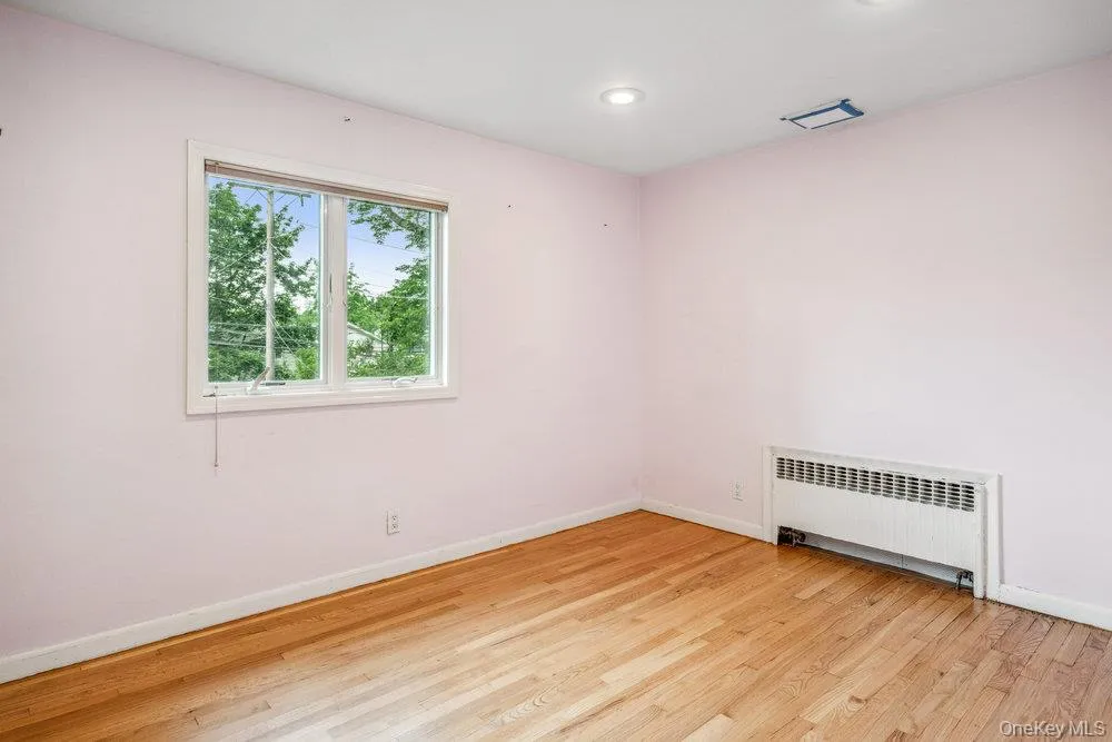 Unfurnished room featuring radiator heating unit, light wood finished floors, and recessed lighting Unfurnished room featuring radiator heating unit, light wood finished floors, and recessed lighting