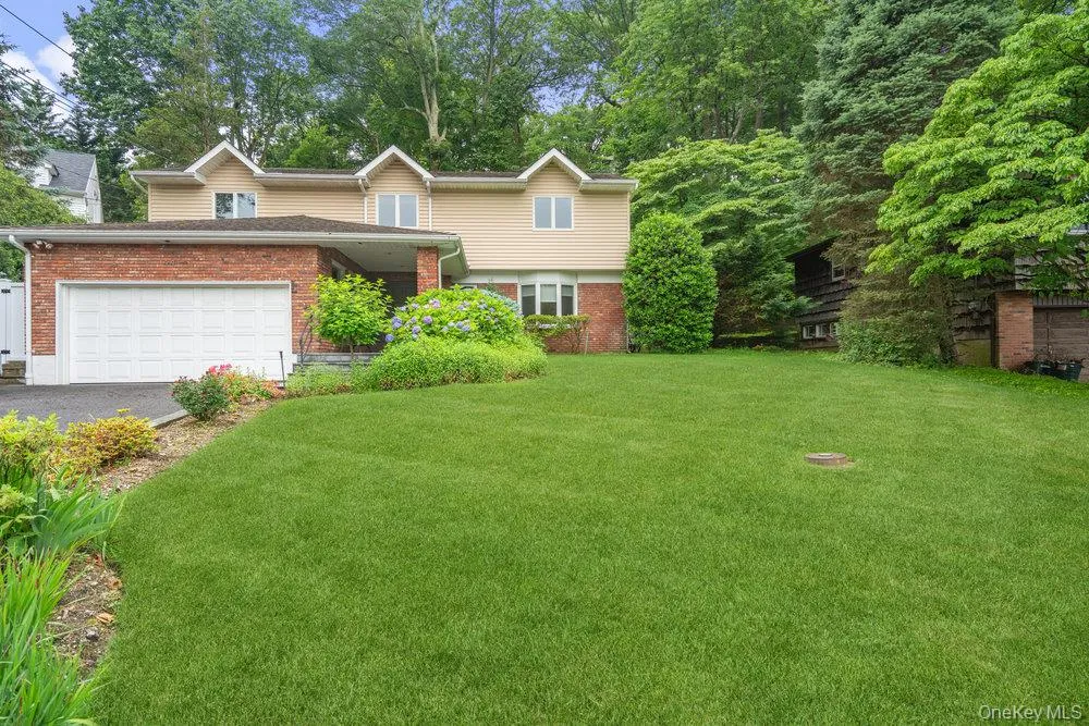 View of front facade featuring brick siding, a front yard, driveway, and a garage View of front facade featuring brick siding, a front yard, driveway, and a garage