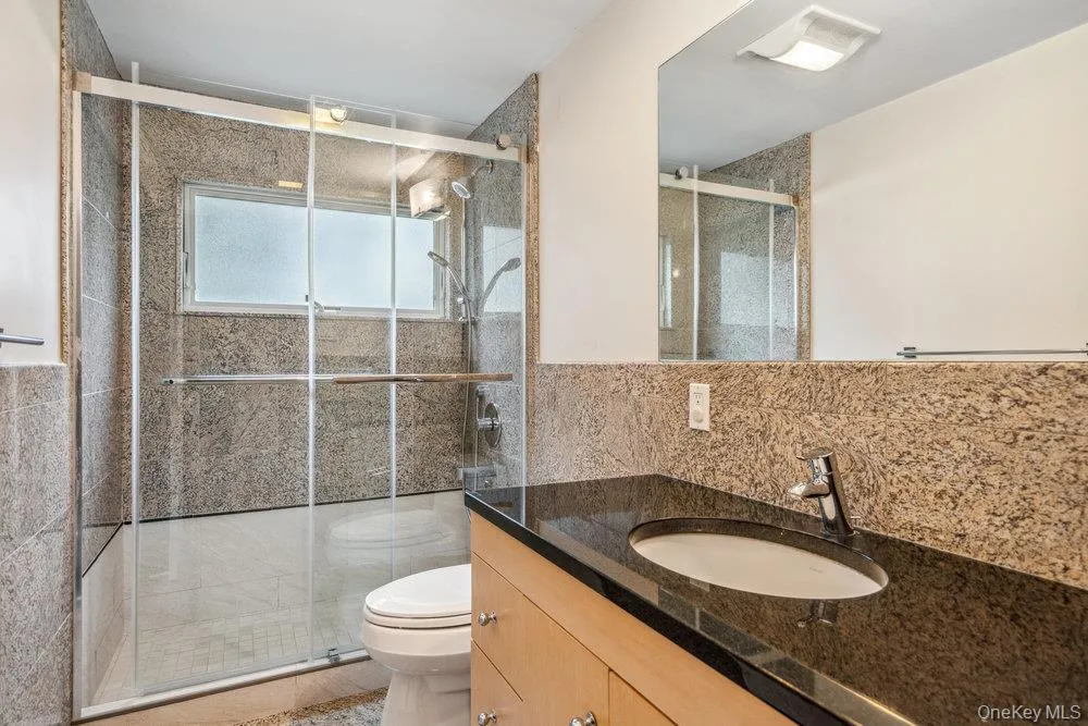 Full bathroom featuring vanity, a stall shower, tile walls, and decorative backsplash Full bathroom featuring vanity, a stall shower, tile walls, and decorative backsplash
