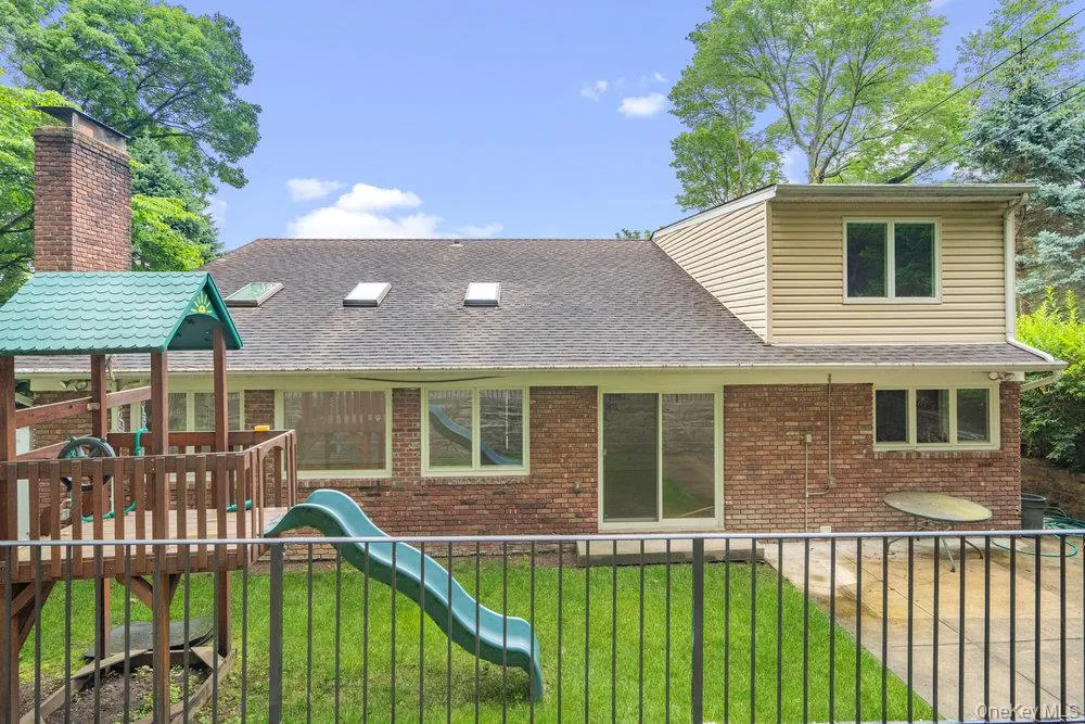 Back of property with a playground, brick siding, and roof with shingles Back of property with a playground, brick siding, and roof with shingles