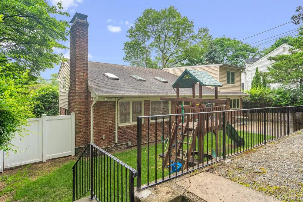 View of front facade with a fenced backyard, a playground, brick siding, and roof with shingles View of front facade with a fenced backyard, a playground, brick siding, and roof with shingles