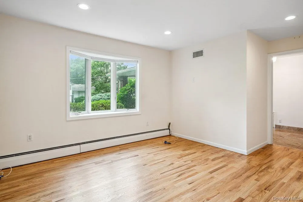 Unfurnished room featuring baseboard heating, light wood-type flooring, and recessed lighting Unfurnished room featuring baseboard heating, light wood-type flooring, and recessed lighting